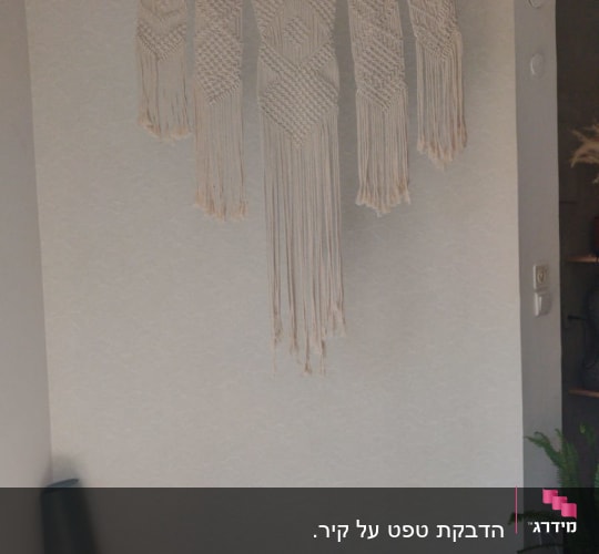 קיר עם טפט בהיר ודוגמת מקרמה תלויה